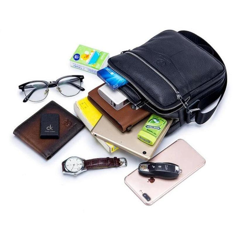 Bolso ejecutivo de piel negro para hombre con objetos personales como cartera, reloj, tablet y llaves.