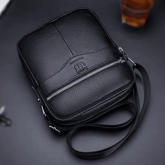 Bolso ejecutivo negro de piel premium con correa crossbody y cierre metálico, estilo urbano.