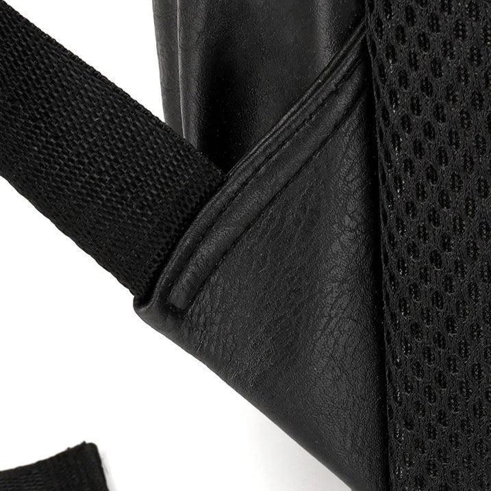 Detalle de mochila masculina compacta en cuero negro con correa resistente y malla transpirable
