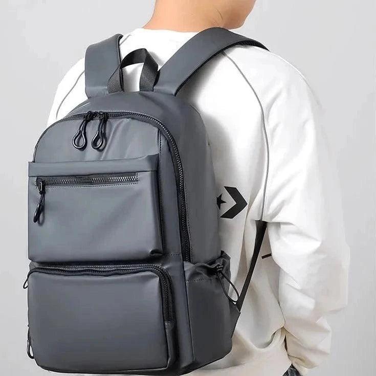 Hombre usando mochila urbana impermeable gris con múltiples compartimentos