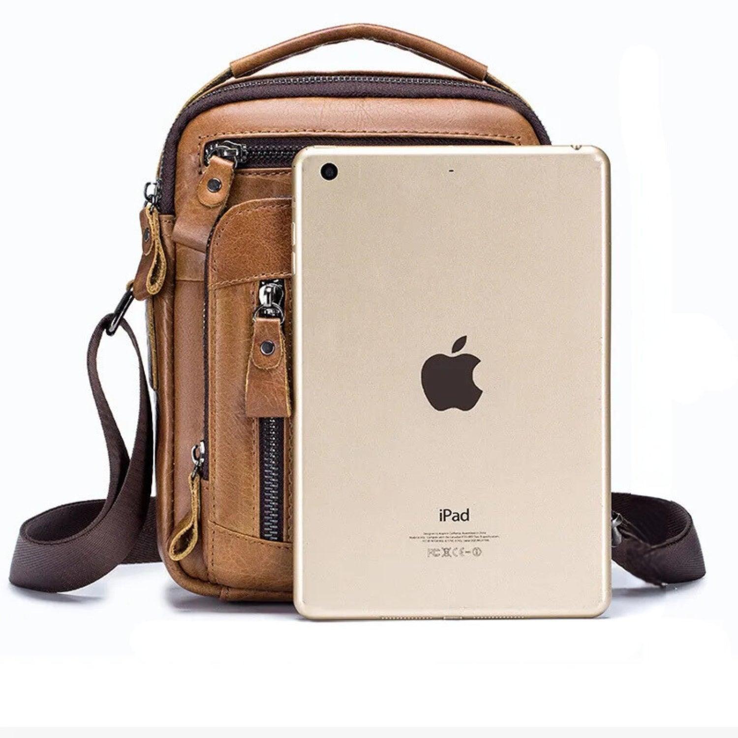 Bolso crossbody ejecutivo compacto de piel marrón con correa ajustable, junto a una tablet.